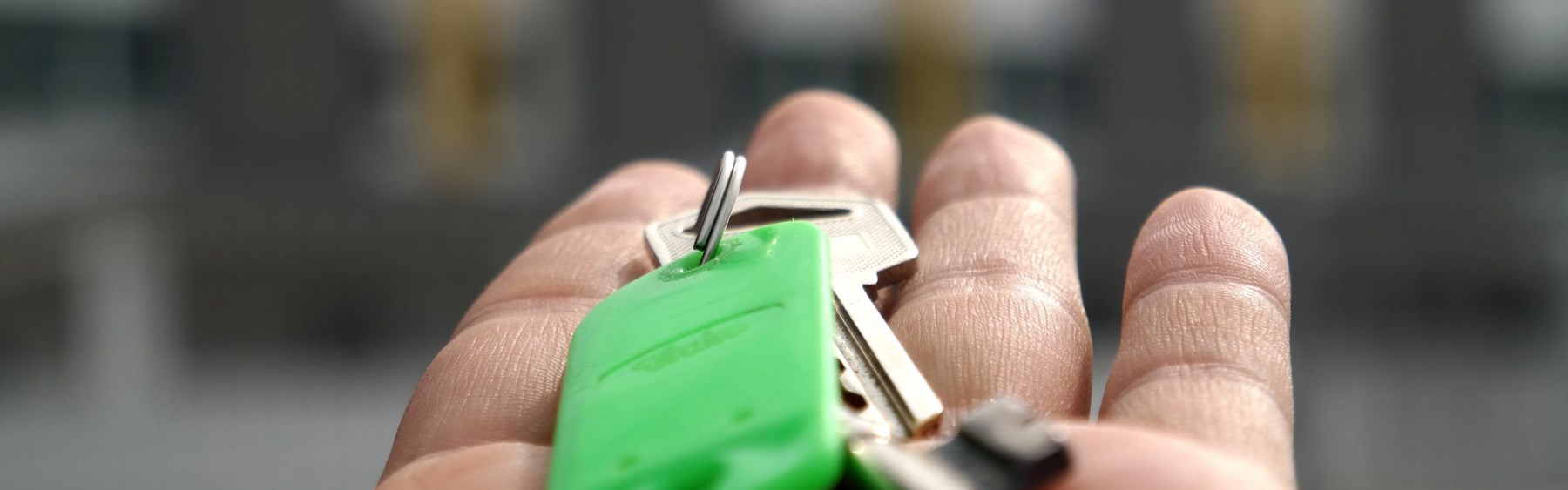 Udstrakt hånd med nøgle. Nøglen sidder fast i en grøn nøglering.
